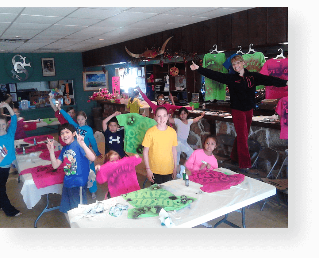 A group of people standing around tables with shirts on them.